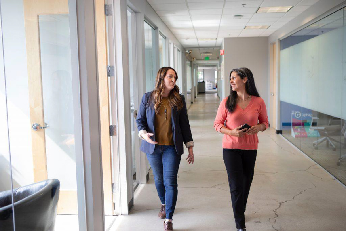 Two professional women walking down hallway