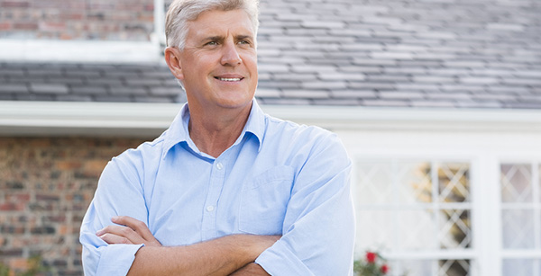 Man with crossed arms in front of house