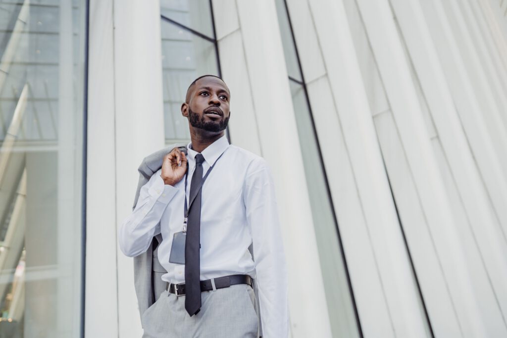Businessman in formal attire posing in front of modern office building facade.