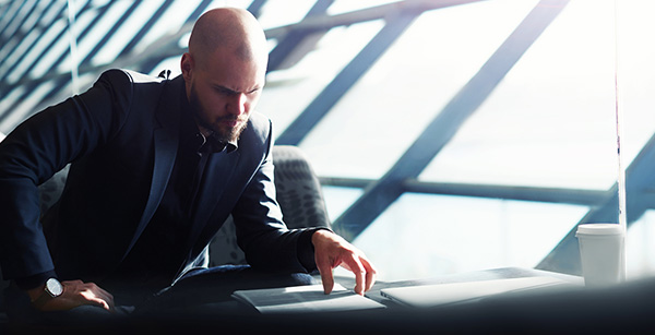Bearded man in business suit and shaved head looking at desk