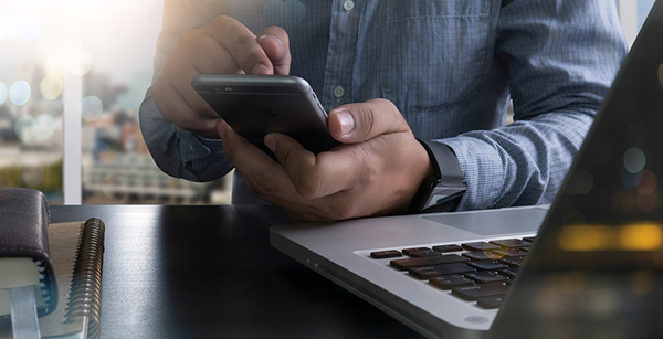 Man using smartphone while laptop open