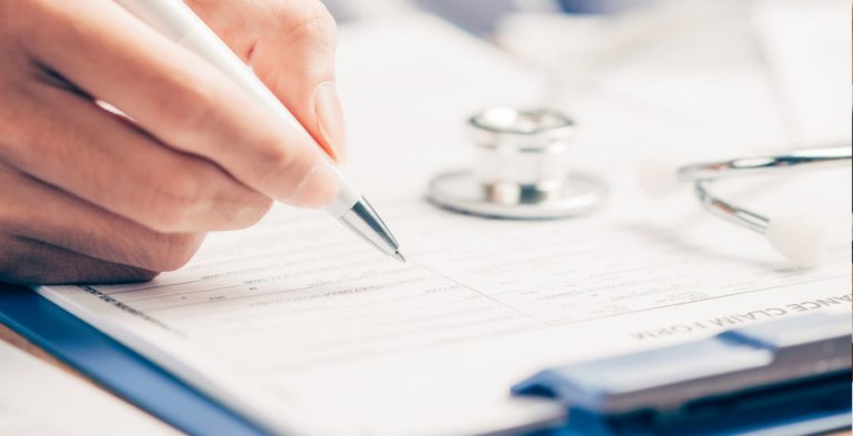 Doctor writing on clipboard paper