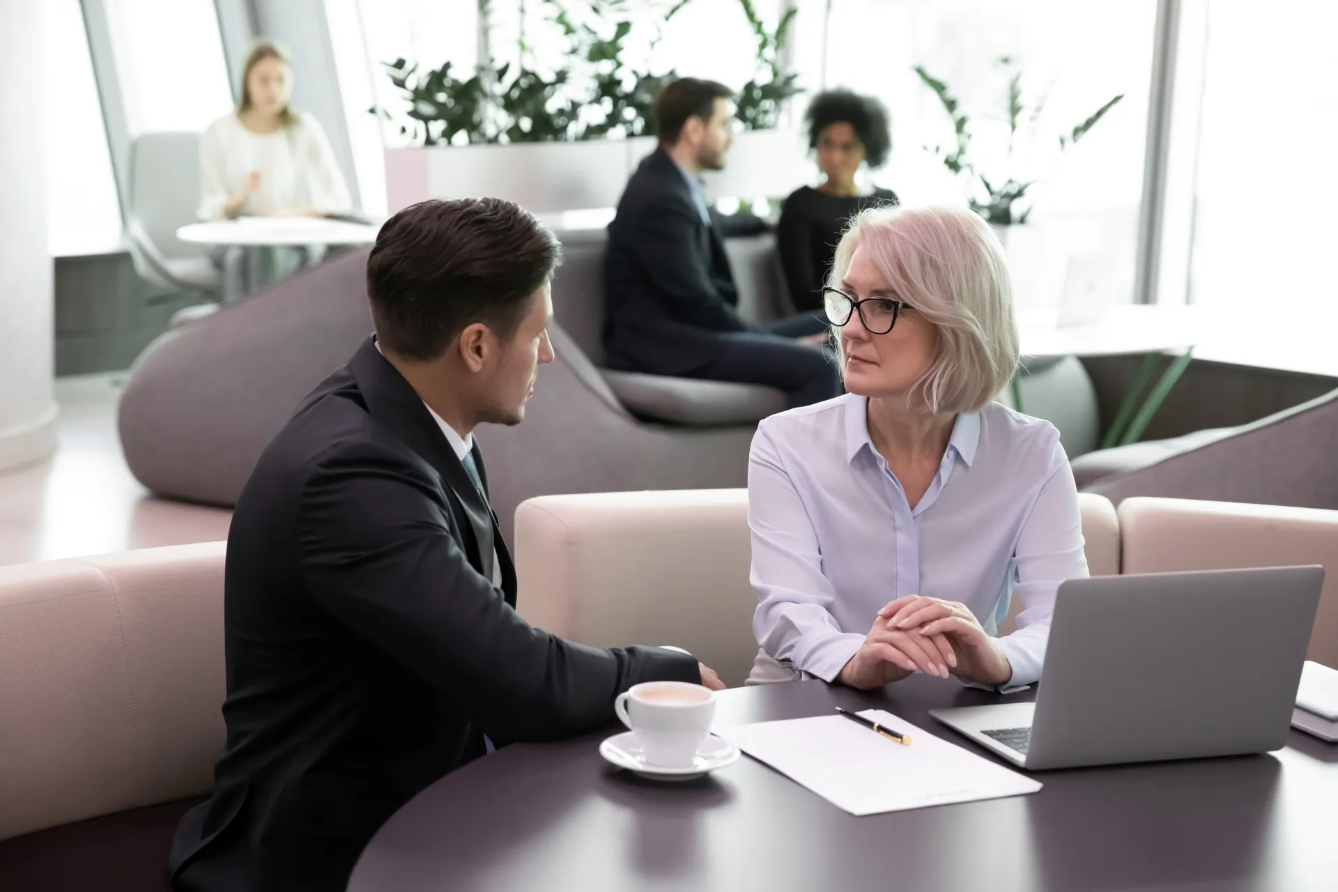 Middle-aged businesswoman bank manager during formal appointment with client solving lending leasing documentation.